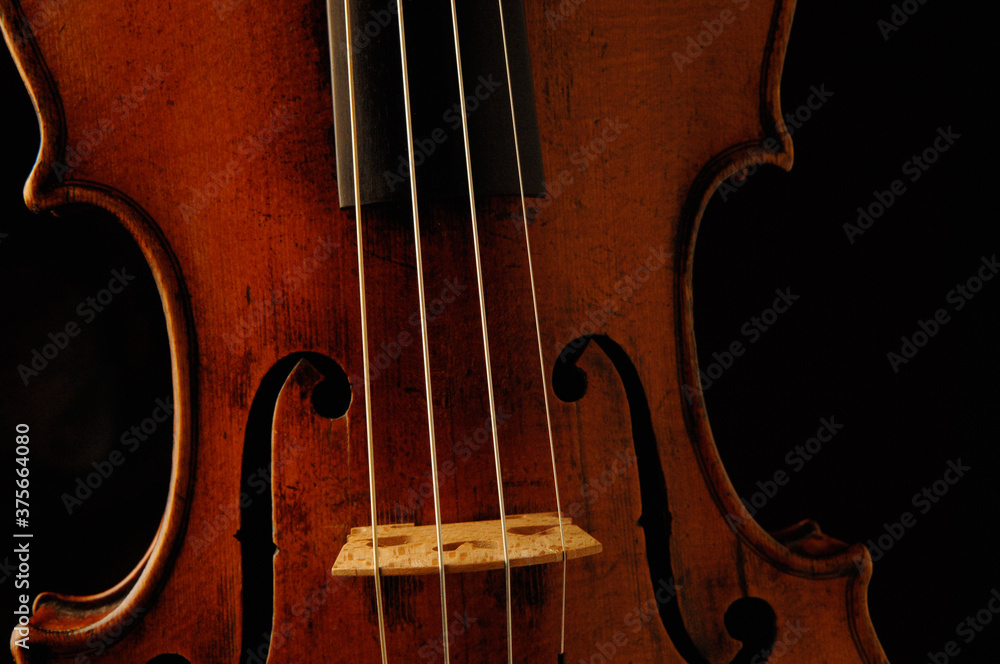 Close up a antique French volin with dramatic lighting on black background Close up a antique French volin with dramatic lighting on black background
