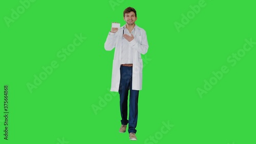 Walking Male Doctor showing empty white box of pills on a Green Screen, Chroma Key. photo