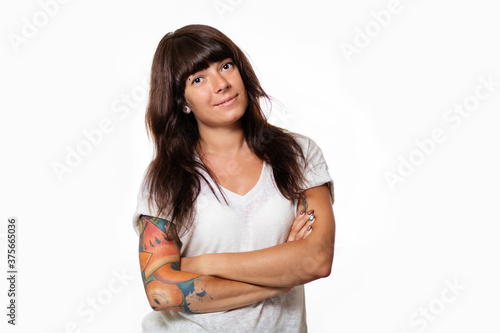 Portrait of a smiling woman with piercings and tattoos, arms crossed. White background. Copy space. The concept of advertising and emotions © _KUBE_
