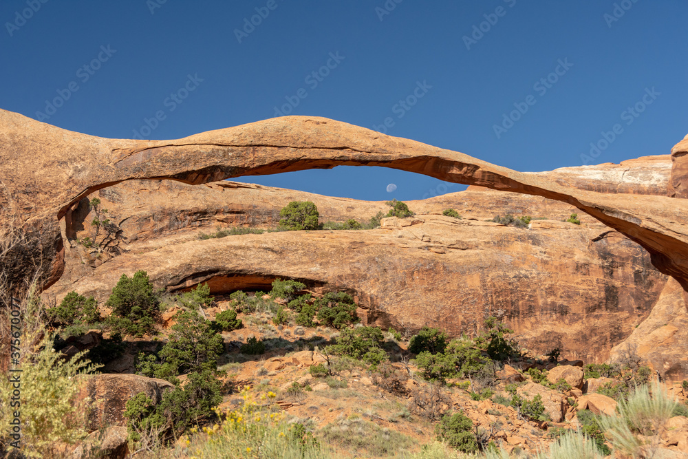 Moon rising from the hill is framed by a natural stone arch and resembles an eye with its pupil - Arches National Park, UT - USA