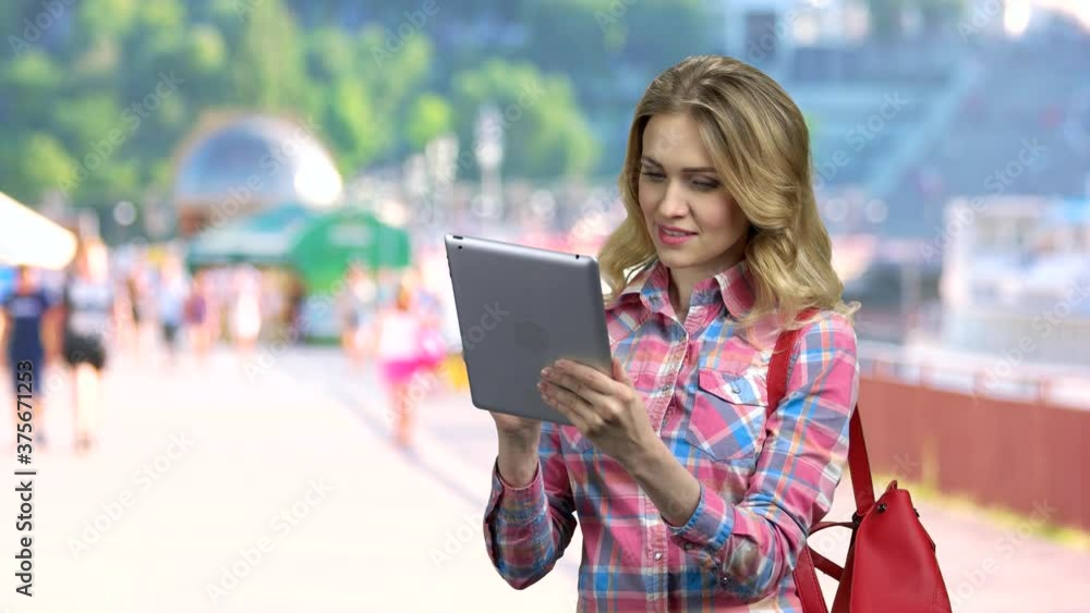 Young woman tourist using digital tablet. Pretty caucasian girl using app on computer tablet. Blurred city background. Young woman tourist using digital tablet. Pretty caucasian girl using app on computer tablet. Blurred city background.