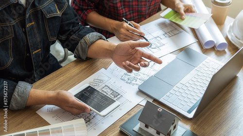 Interior designer and Architect choosing color in color swatch samples chart for house coloring selection in office with blueprint. Construction concept.