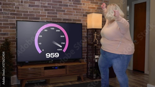 A young woman dances in her living room in front of her TV because she's happy to have 1 gigabit broadband Internet service. Slow motion. Screen content customizable upon request.	