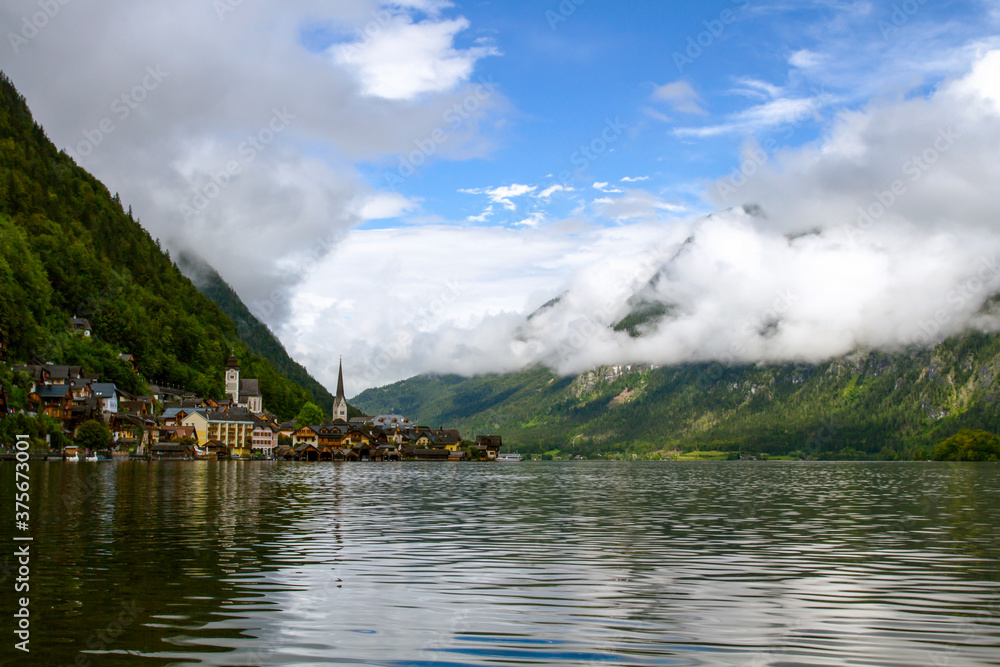 Hallstatt, Austria. View to Hallstattersee Lake and Alps mountains summits. Ancient houses at lake banks with chapel. Tourism in Austria. The Alps are a popular tourist destination.  Europe.