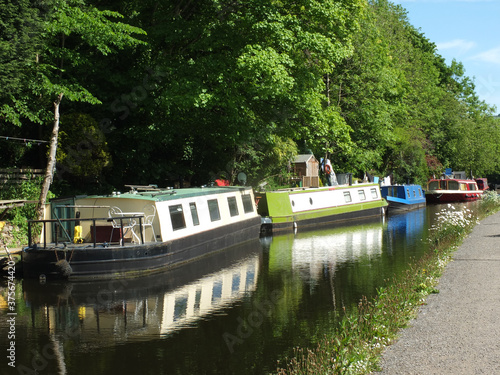 canal boats moored opposite the path on the rochdale canal near hebden bridge surrounded by trees in summer sunlight photo