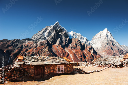 Traditional nepalese houses and view of Taboche and Cholatse peaks in Himalaya mountains. Khumbu valley, Everest region, Nepal. photo