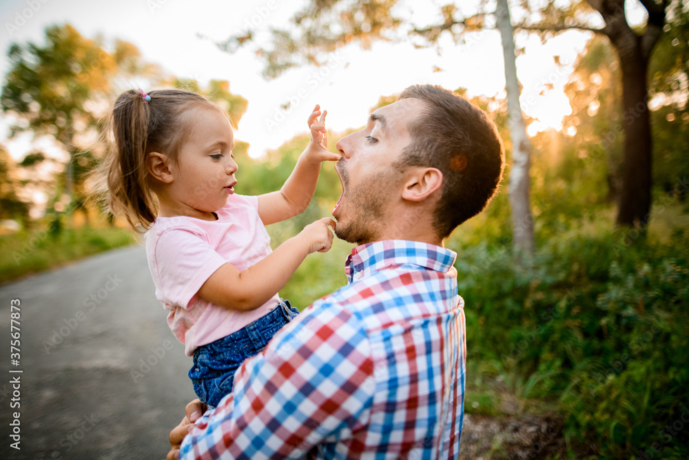 cheerful little girl sits in her father's arms and having fun cheerful little girl sits in her father's arms and having fun