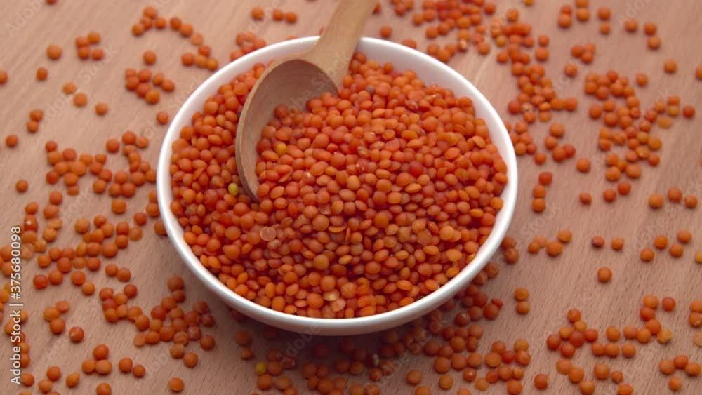 Red lentils in a bowl with a spoon rotates on a wooden background. ProRes 422 Red lentils in a bowl with a spoon rotates on a wooden background. ProRes 422