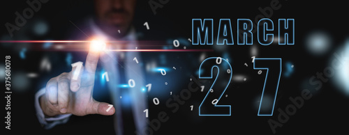 march 27th. Day 27 of month,advertising or high-tech calendar, man in suit presses bright virtual button spring month, day of the year concept