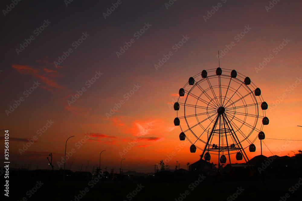 The silhouette of a sunset ferris wheel ride at dusk
