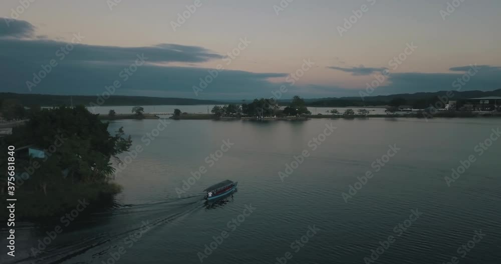 Beautiful drone aerial shot of a boat driving through the lake of Peten Itza, Guatemala during sunset Beautiful drone aerial shot of a boat driving through the lake of Peten Itza, Guatemala during sunset
