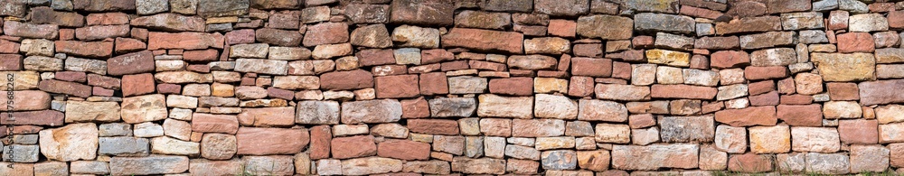 Fototapeta premium Trockenmauer aus Natursteinen an einem Weinberg als Panorama