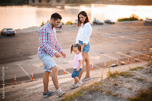 happy married couple with small cute child walking near the river © fesenko