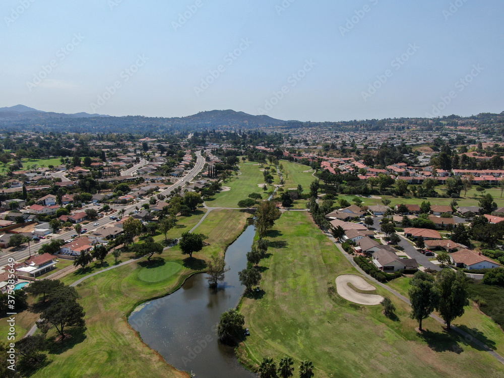 Aerial view of golf in middle class neighborhood surrounded with residential house, and mountain on the background in San Diego, South California, USA.