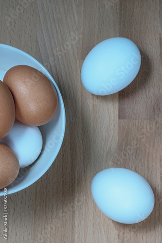 several fresh chicken eggs in a ceramic cup on a wooden background. Healthy eating concept