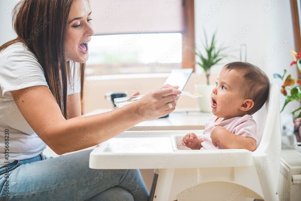 Mother feed her little daughter with a spoon Mother feed her little daughter with a spoon