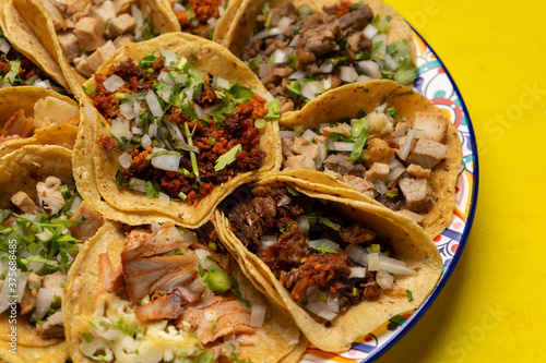 Assortment of mexican tacos on yellow background photo