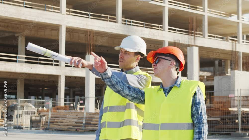 Professional builders standing in front of construction site. Office building and crane background. Professional builders standing in front of construction site. Office building and crane background.
