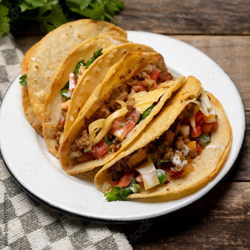 Mexican hard-shell tacos with meat and fresh sauce on wooden background