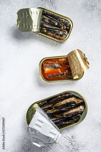 Assorted canned fish in a tin sardine, smoked sardine, mackerel. Grey wooden background. Top view