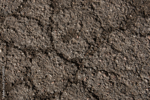 Texture of an old asphalt road with cracks and water stains close-up.