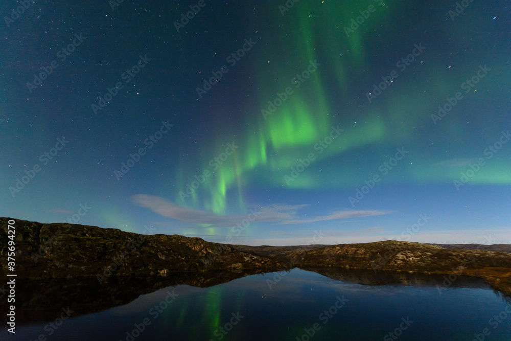 Night sky. Northern lights aurora stars hills reflection in water.