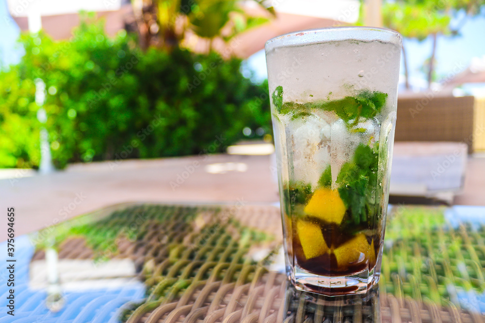 Ice mojito cocktail with lemon and mint on the terrace of the bar. Alcoholic drinks. Relaxation and party time. Copy space for text., selective focus Ice mojito cocktail with lemon and mint on the terrace of the bar. Alcoholic drinks. Relaxation and party time. Copy space for text., selective focus
