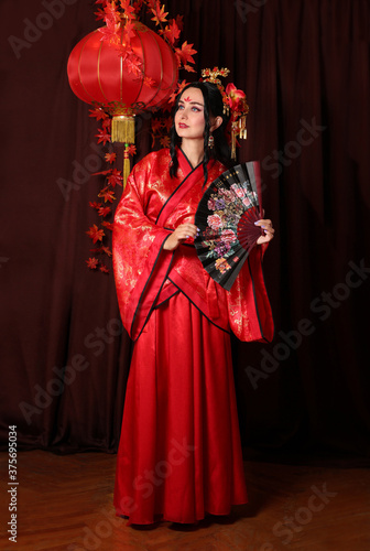 a woman in red Chinese national traditional costume. Chinese woman with hairpins in her hair. girl with a Chinese fan red Chinese lantern 
