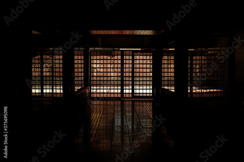 Dark interior of a prison and a barred exit gate.