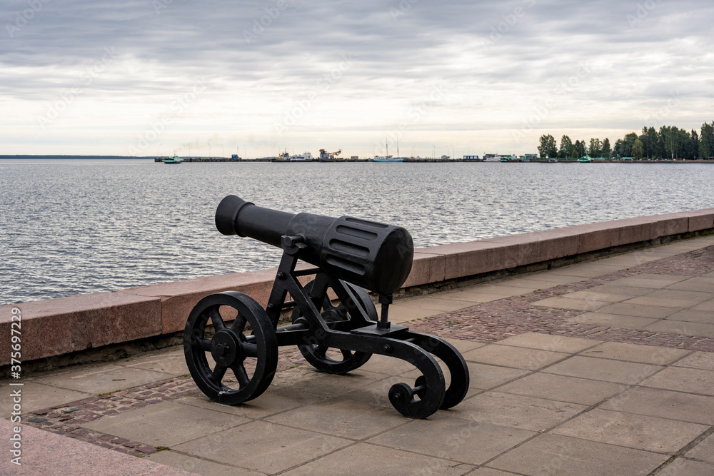 antique cast iron black cannon on a pedestal on the embankment antique cast iron black cannon on a pedestal on the embankment