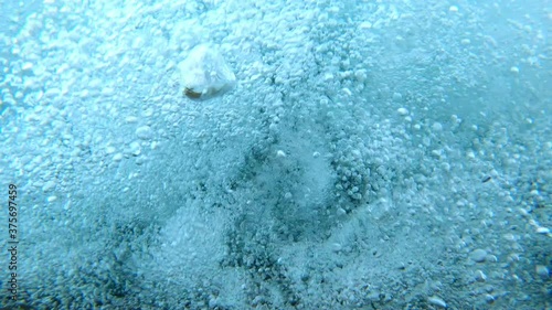 Bubbles in river from above while falling underwater as if drowning in strong river current.