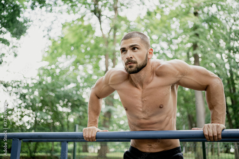 a confident man of athletic build does sports and exercises. he thinks about his body and health. stadium in the Park. short hair, beard, naked torso. Caucasian appearance