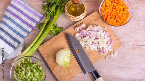 Cooking vegetable filling of onions carrots and celery, chopped ingredients for Mirepoix or Soffritto with olive oil on a wooden table.