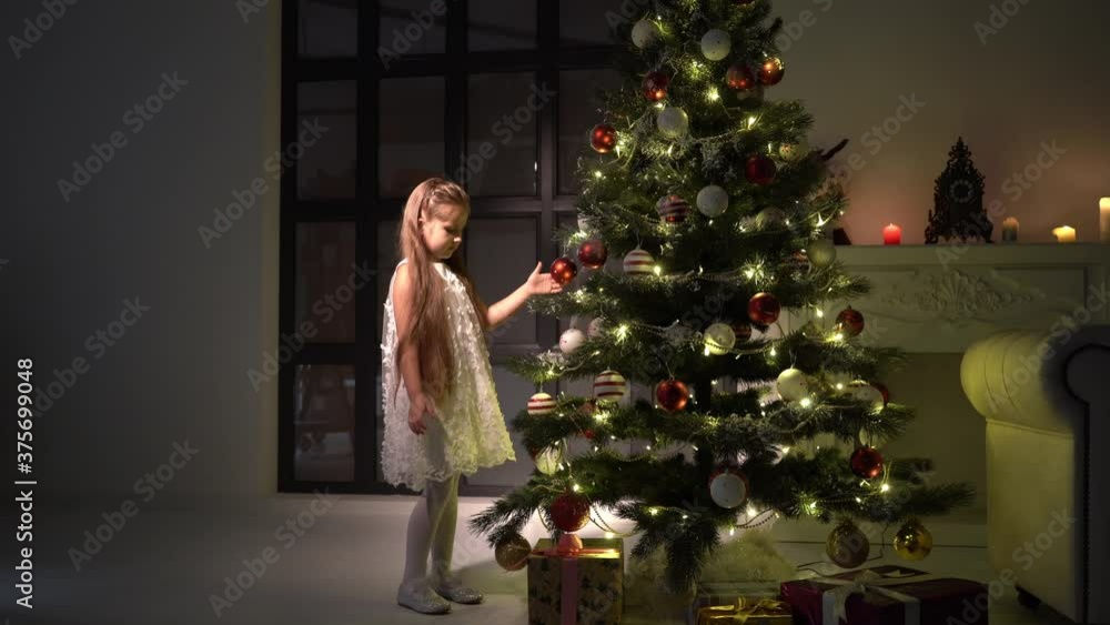 Little girl decorates a Christmas tree. New Year concept, family holidays. Little girl decorates a Christmas tree. New Year concept, family holidays.