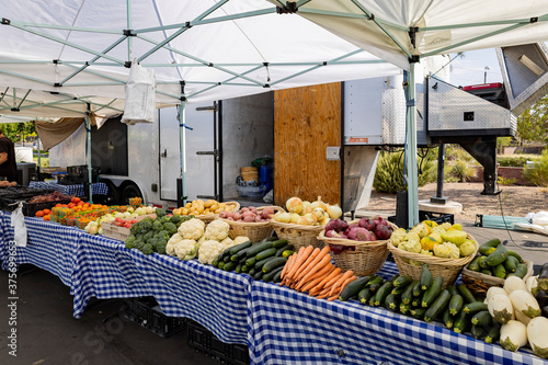 Farmer selling many different vegetables and fruits in a booth