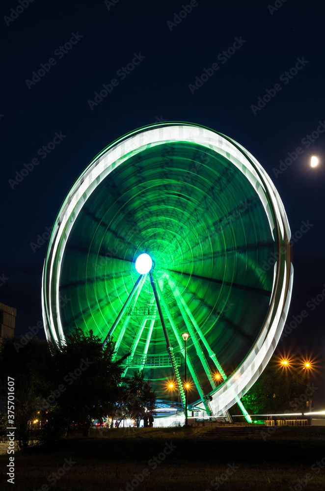 Moving ferris wheel near Vistula river in Cracow at night, Poland