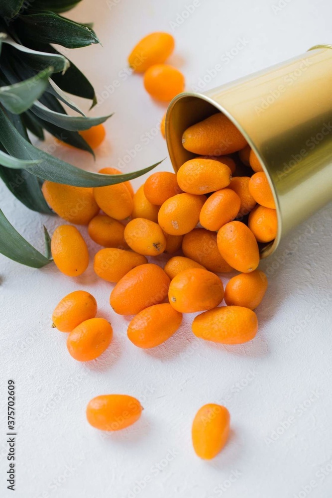 exotic kumquat fruit spilled out of a bucket on a white background