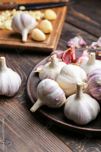 Plate with fresh garlic on wooden background