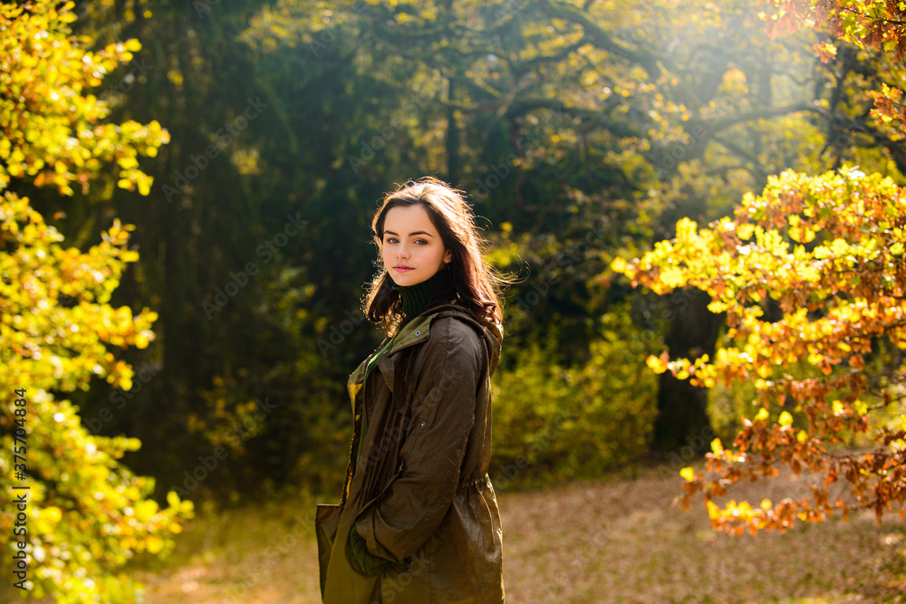 Beautiful teenager in fall park. Cheerful autumn teen with long healthy hair holding yellow maple leaf outdoors in sunny day. Beautiful teenager in fall park. Cheerful autumn teen with long healthy hair holding yellow maple leaf outdoors in sunny day.