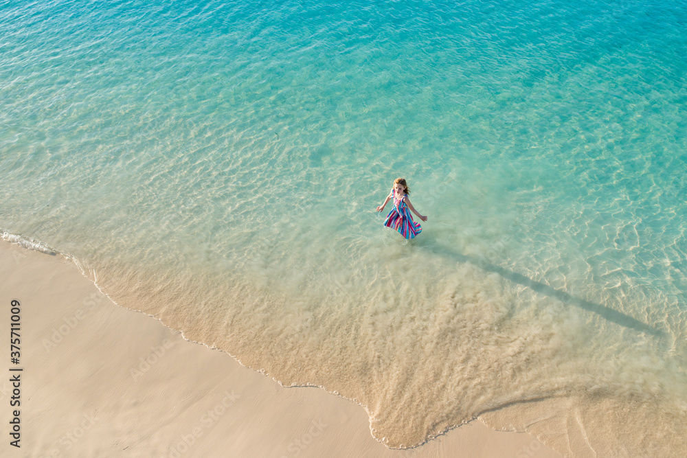 Aerial View of Little Girl Wearing a Dress Wading In Ocean at Tropical Beach on Family Vacation Aerial View of Little Girl Wearing a Dress Wading In Ocean at Tropical Beach on Family Vacation