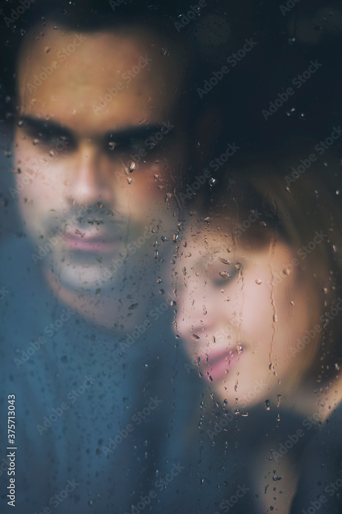 Couple standing at the window watching the rain Couple standing at the window watching the rain