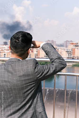 a man looking at the smoke in the distance. Concept of super hero looking for somebody to help. 