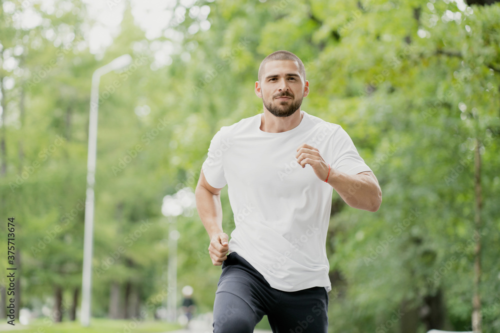 athletic man dark-haired Caucasian appearance running on a treadmill, sports training in a green Park athletic man dark-haired Caucasian appearance running on a treadmill, sports training in a green Park