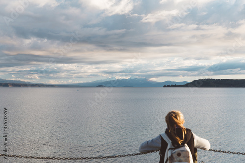 Young woman looking at the mountains behind the lake photo