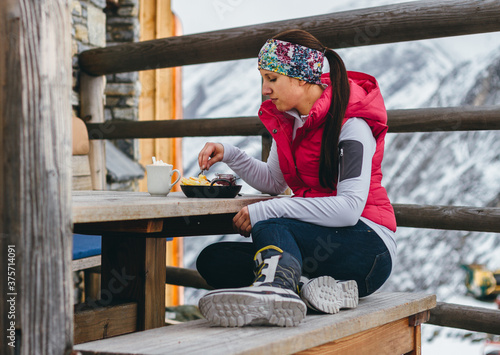 young woman in snowboots eating a kaiserschmarrn in alpine senery photo