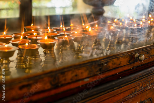 Dharamsala Temple candles in brass holders glow through worn glass cabinet door