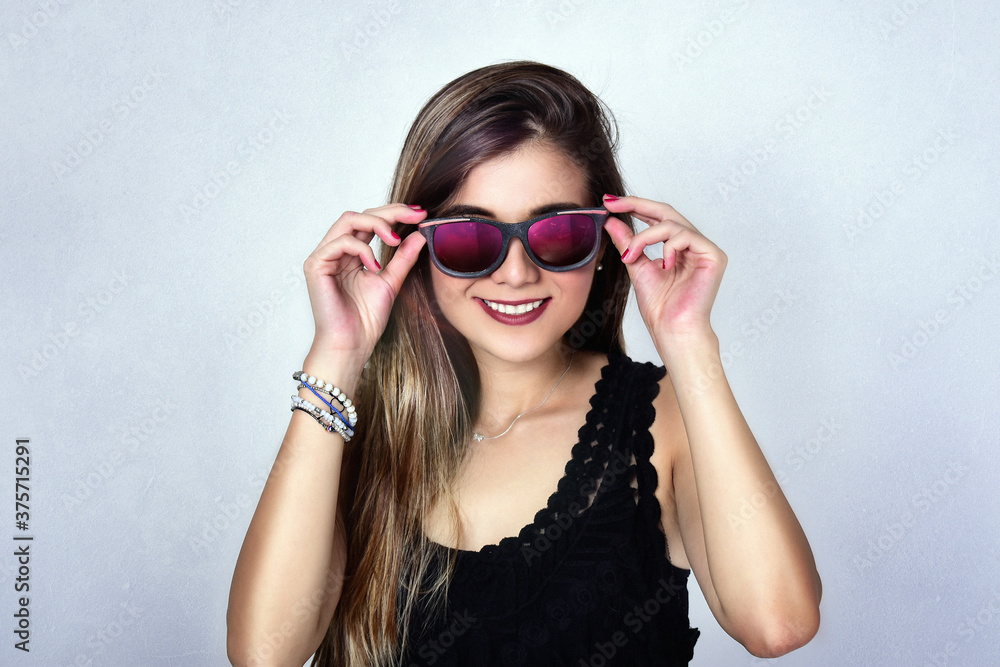 Beautiful brunette laughing woman wearing glasses and black shirt on gray background Beautiful brunette laughing woman wearing glasses and black shirt on gray background