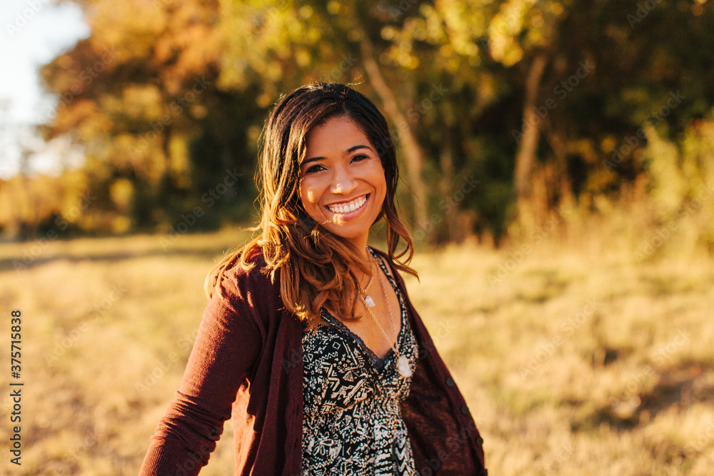 Portrait of a smiling young African American woman dancing in a field while the sun is setting. Portrait of a smiling young African American woman dancing in a field while the sun is setting.