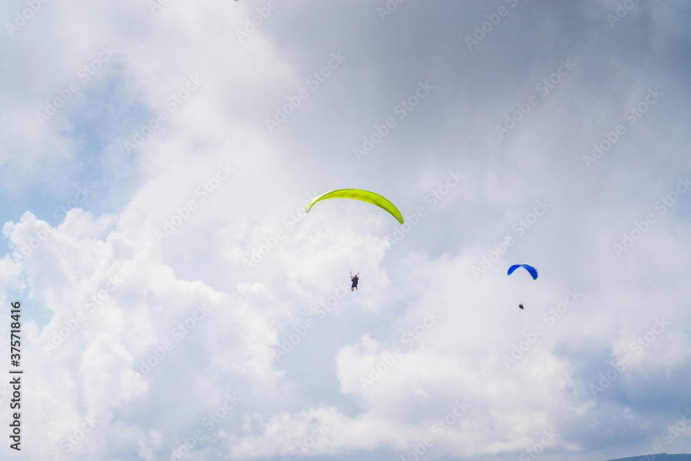 Paragliding in the cloudy blue sky.