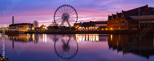 Panorama of Motlawa River and Ferris wheel with water reflection in Old Town of Gdansk at night, Poland
